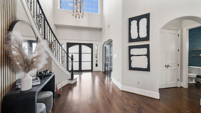 foyer with a high ceiling, dark hardwood / wood-style flooring, an inviting chandelier, and a wealth of natural light