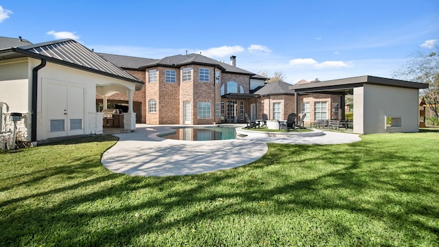 rear view of property featuring an outdoor kitchen, a patio area, and a lawn