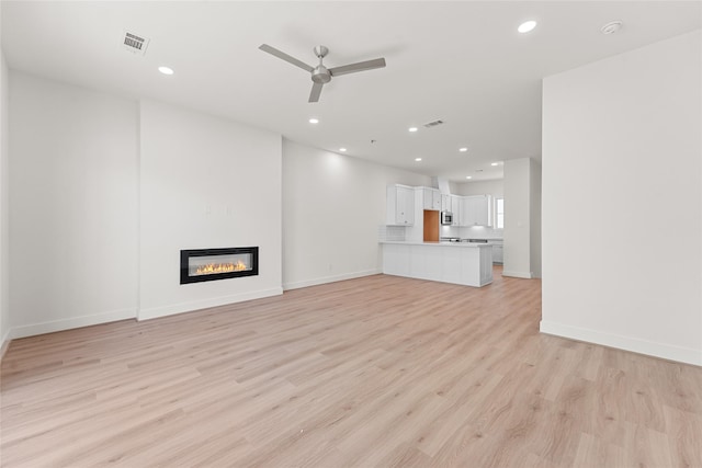 unfurnished living room featuring ceiling fan and light wood-type flooring