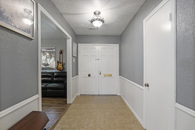 hall with light hardwood / wood-style flooring and a textured ceiling