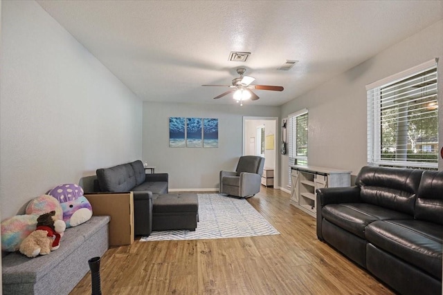 living room featuring a textured ceiling, light hardwood / wood-style flooring, and ceiling fan