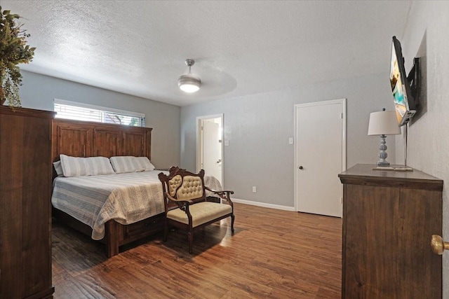 bedroom with a textured ceiling, ceiling fan, and dark wood-type flooring