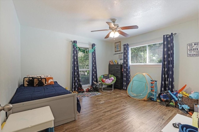 bedroom featuring hardwood / wood-style floors, ceiling fan, and multiple windows