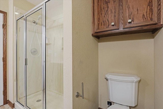 bathroom featuring a shower with door and toilet