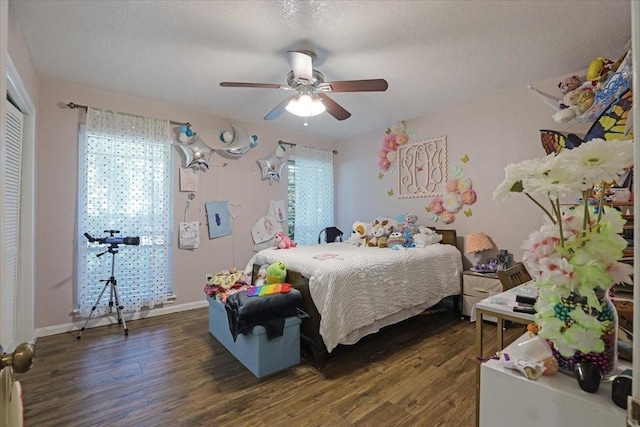 bedroom with ceiling fan, dark hardwood / wood-style flooring, a textured ceiling, and multiple windows