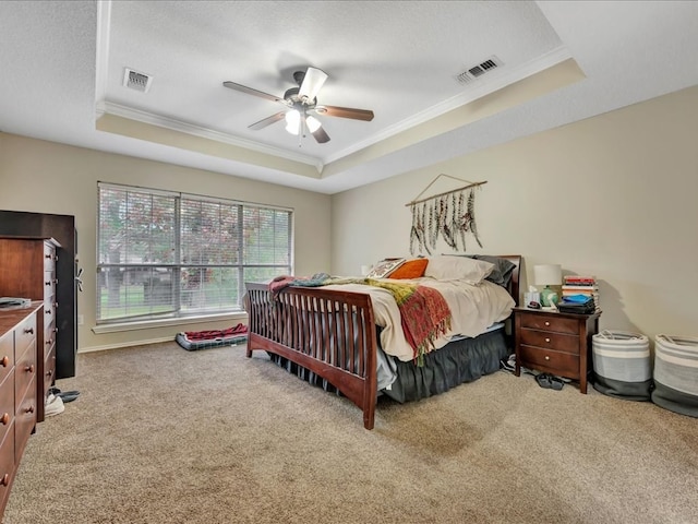 carpeted bedroom with ceiling fan, crown molding, and a tray ceiling