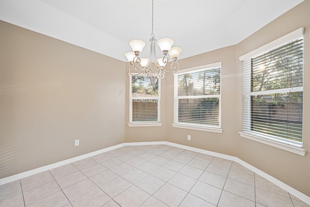 tiled empty room featuring an inviting chandelier