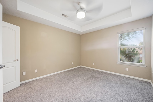 carpeted empty room featuring a raised ceiling and ceiling fan