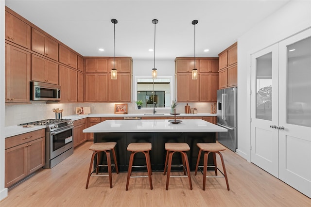 kitchen with a kitchen breakfast bar, premium appliances, light hardwood / wood-style flooring, and a kitchen island