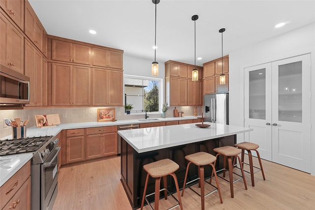 kitchen with a breakfast bar, a center island, stainless steel appliances, and decorative light fixtures