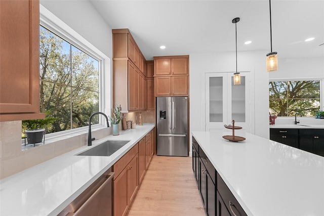 kitchen featuring sink, hanging light fixtures, plenty of natural light, and appliances with stainless steel finishes