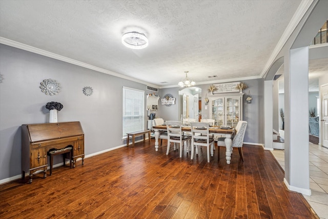 dining area with an inviting chandelier, ornamental molding, hardwood / wood-style floors, and a textured ceiling