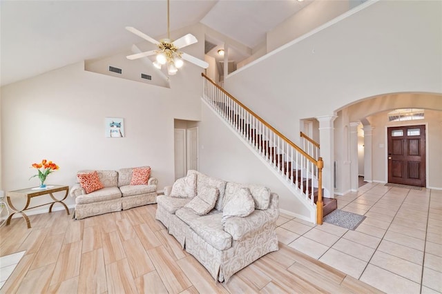 living room featuring ceiling fan, light wood-type flooring, high vaulted ceiling, and ornate columns