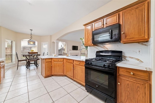 kitchen with kitchen peninsula, decorative columns, black appliances, light tile patterned floors, and pendant lighting