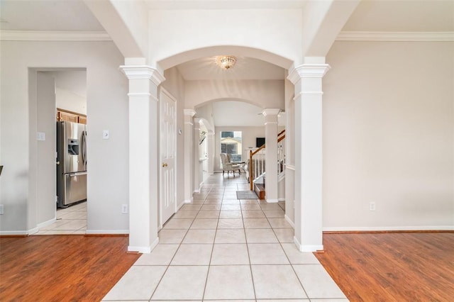 hallway with decorative columns, light tile patterned floors, a chandelier, and ornamental molding