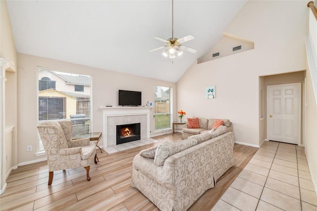 living room with ceiling fan, a fireplace, and a towering ceiling