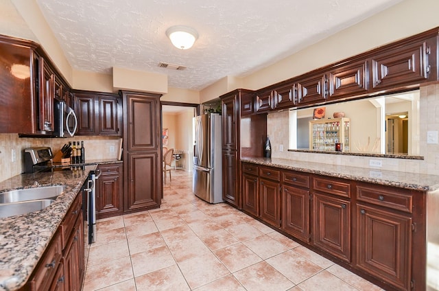 kitchen featuring decorative backsplash, light stone countertops, and stainless steel appliances