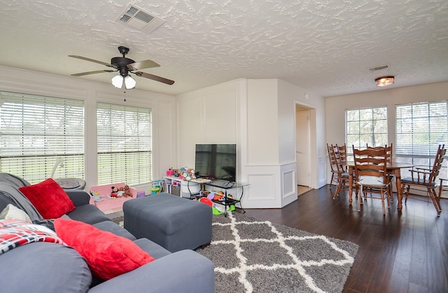 living room featuring ceiling fan, dark hardwood / wood-style flooring, plenty of natural light, and a textured ceiling