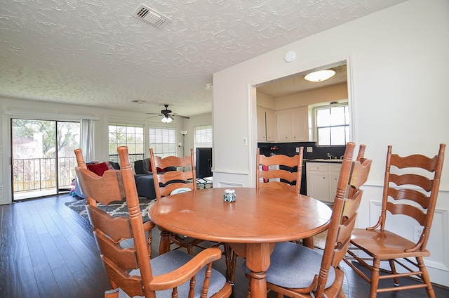 dining space with a textured ceiling, ceiling fan, and dark hardwood / wood-style floors