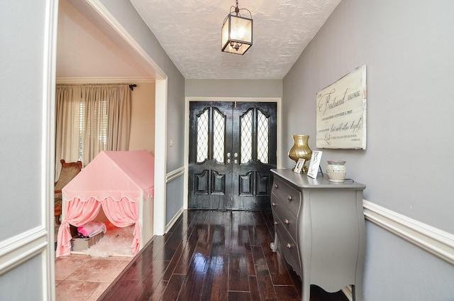 foyer entrance featuring plenty of natural light, a textured ceiling, and dark wood-type flooring