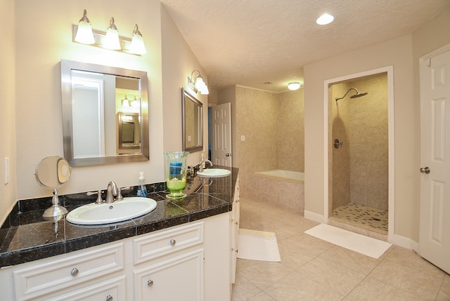 bathroom featuring tile patterned floors, vanity, shower with separate bathtub, and a textured ceiling