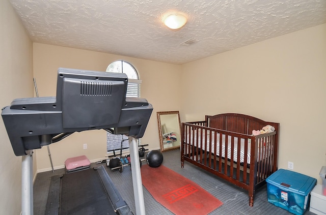 bedroom featuring a crib and a textured ceiling