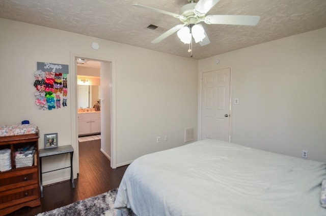 bedroom featuring a textured ceiling, ceiling fan, dark wood-type flooring, and ensuite bath