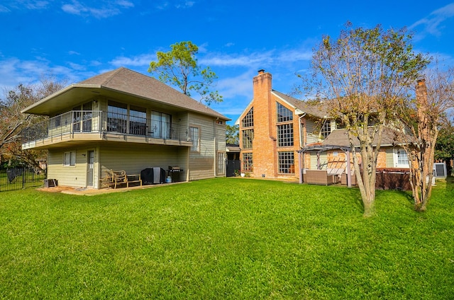 back of property with a yard, a balcony, and cooling unit