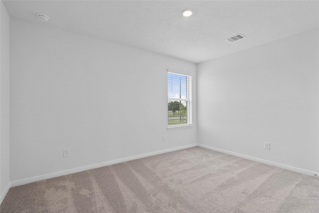 empty room with light colored carpet, baseboards, and visible vents