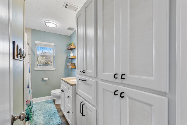 bathroom featuring hardwood / wood-style flooring, vanity, and toilet