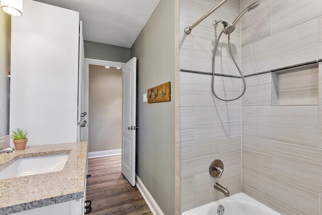 bathroom featuring hardwood / wood-style floors, tiled shower / bath combo, a textured ceiling, and vanity