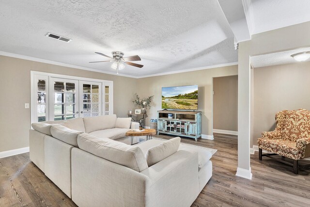 living room with hardwood / wood-style floors, crown molding, a textured ceiling, and french doors