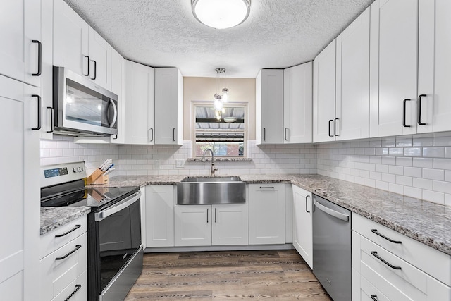 kitchen featuring white cabinets, light stone counters, sink, and appliances with stainless steel finishes