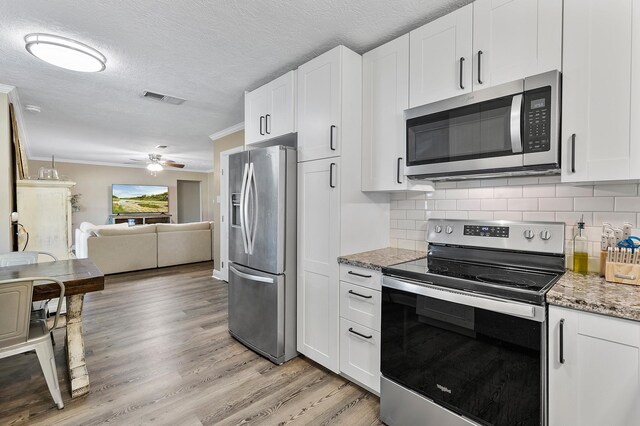 kitchen with decorative backsplash, a textured ceiling, stainless steel appliances, stone counters, and white cabinets