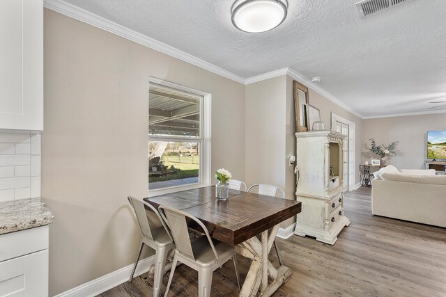 dining space featuring crown molding, a textured ceiling, and light wood-type flooring