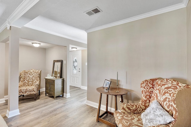 living area with crown molding, light hardwood / wood-style floors, and a textured ceiling