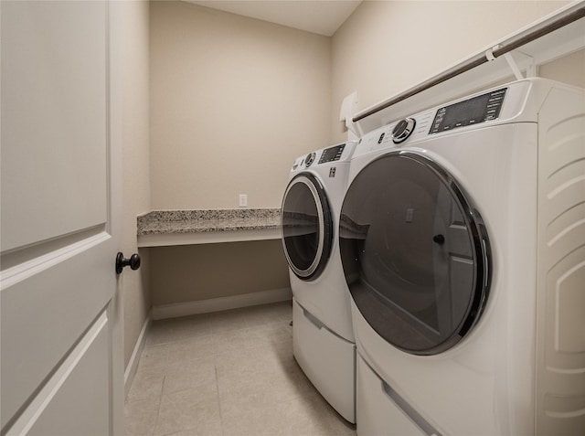 laundry area with light tile patterned floors and washing machine and clothes dryer