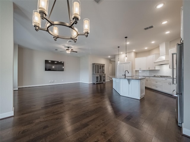 kitchen with premium range hood, a center island with sink, white cabinetry, hanging light fixtures, and gas stovetop