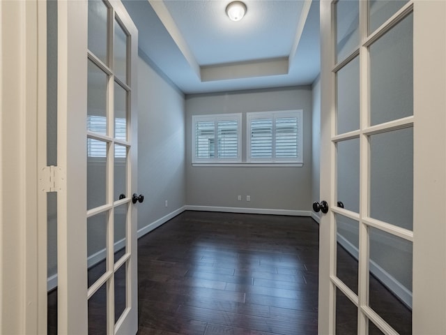 empty room with french doors, dark hardwood / wood-style flooring, and a tray ceiling