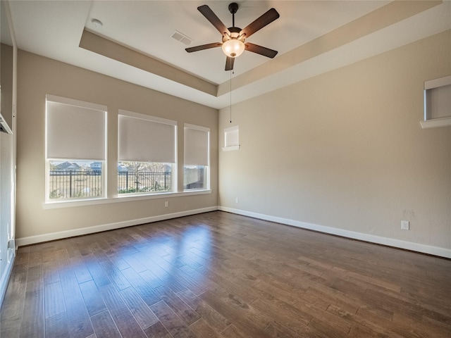 unfurnished room featuring ceiling fan, dark hardwood / wood-style flooring, and a raised ceiling