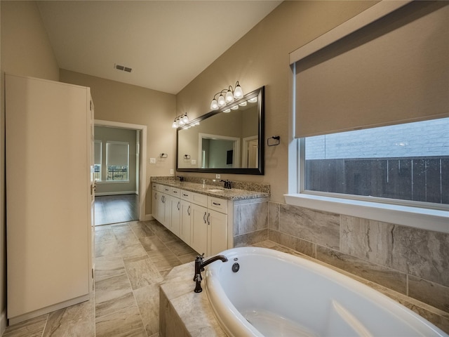 bathroom featuring tiled bath and vanity