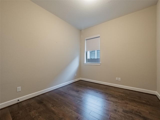 spare room with a textured ceiling, dark hardwood / wood-style floors, and lofted ceiling