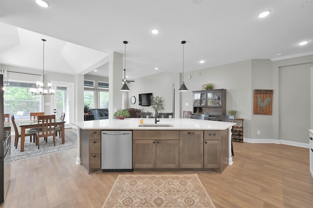 kitchen featuring a large island, sink, light hardwood / wood-style flooring, stainless steel dishwasher, and decorative light fixtures