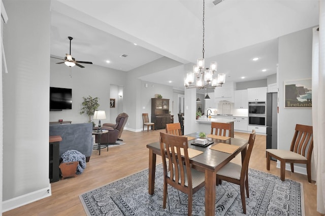 dining area featuring ceiling fan with notable chandelier, light wood-type flooring, and sink