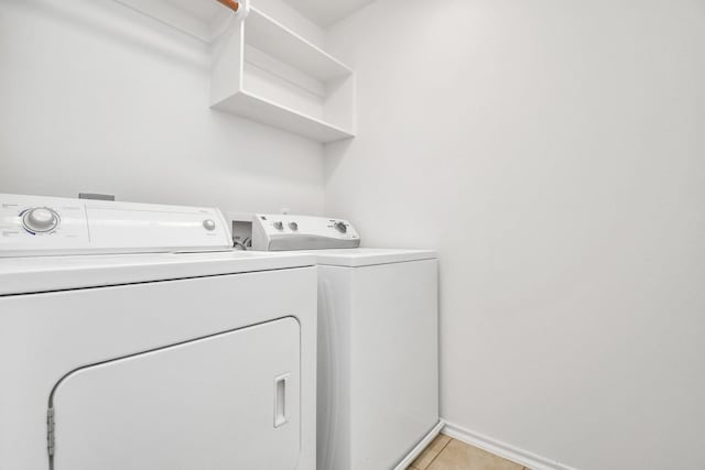 laundry area with washer and clothes dryer and light tile patterned floors