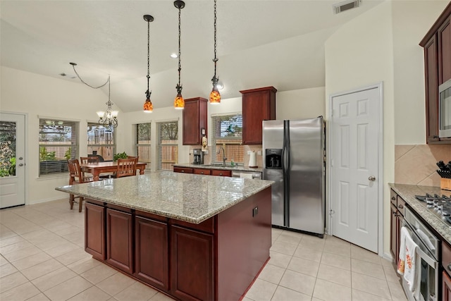 kitchen featuring hanging light fixtures, vaulted ceiling, a notable chandelier, a kitchen island, and stainless steel appliances