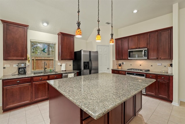 kitchen featuring sink, hanging light fixtures, a kitchen island, light stone counters, and stainless steel appliances