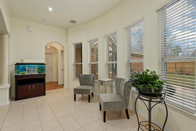 sitting room featuring light tile patterned floors, decorative columns, and a wealth of natural light