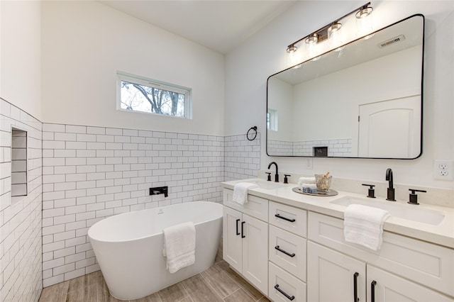 bathroom featuring a bathtub, vanity, and tile walls