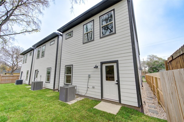 back of property with a lawn and central air condition unit